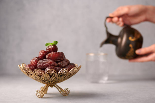 date fruits or kurma in vintage arabic dish and jug of water at grey concrete background. dates and water is ramadan meal. ramazan iftar food. - fast water imagens e fotografias de stock