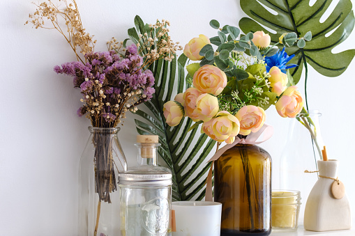 Fake flowers in vases on white wall background