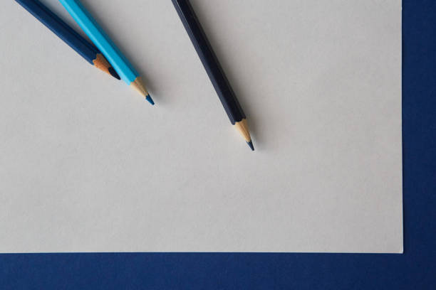 Several colored pencils of blue hues lie on a bright blue-white background