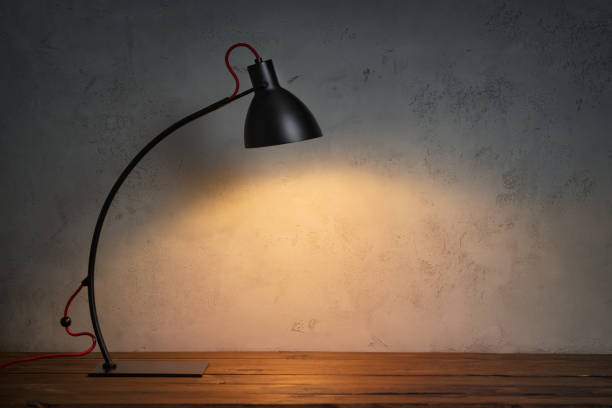 istock Classic lamp on wooden desk and concrete wall 1220559418