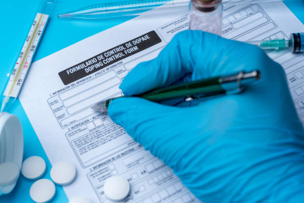 A gloved hand writes on a doping control form. Blank doping control, syringe and blood close-up. Medical research. A gloved hand writes on a doping control form. anti doping stock pictures, royalty-free photos & images