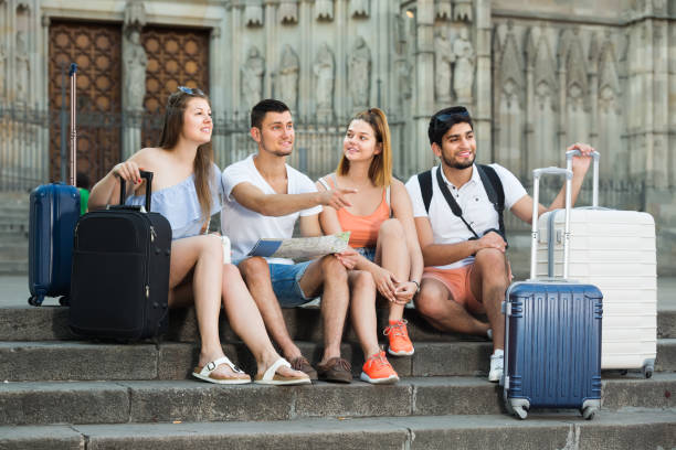 four interested traveling young people searching for direction using paper map in the street of a European town