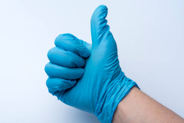 The gloved hand shows the thumbs up. The blue medical glove on the doctor's hand.