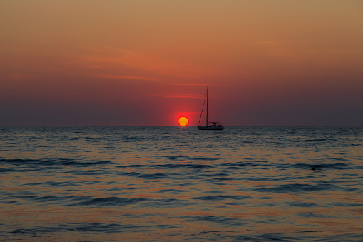 Photo of a sunset over the sea with a boat in backlight photographed from Kamala Beach in Phuket in November 2013