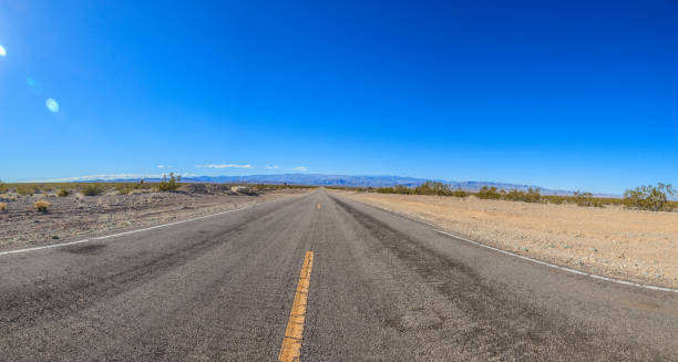 istock Panoramic view of a road through the desert from a ground perspective 1220565420