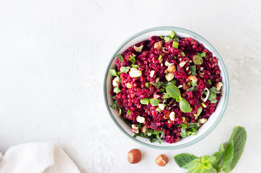 Warm buckwheat, beetroot, nuts and herbs salad, light grey concrete background. Vegetarian and vegan food. Healthy food concept. Top view.