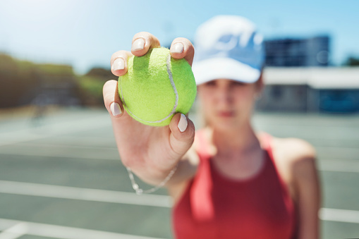 Cropped shot of an unrecognizable sportswoman standing alone and holding a tennis ball during a training session