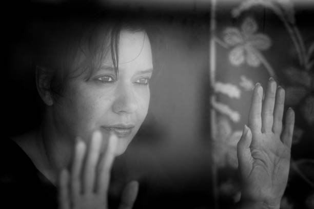 istock Depressed woman looking out of window 1220568066