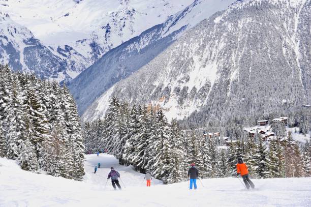 Skiing people in ski resort Courchevel between snowy trees Ski resort Courchevel, Rhône Alps, France on 3rd March, 2020 with skiing people on the slopes between snowy tress courchevel stock pictures, royalty-free photos & images