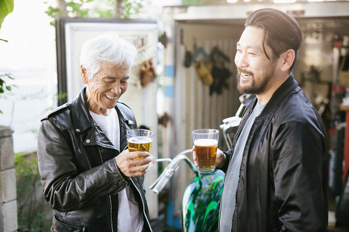 Senior Asian man having a beer with his son
