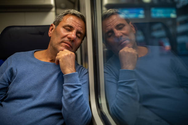 Exhausted mature man taking a nap while traveling by passenger train in Cologne, Germany