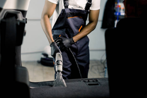 professional cleaning of car interior by wet vacuum machine. clopped image of male african auto service worker cleaning the trunk of the car with vacuum cleaner. view from the car - car cleaning inside of indoors imagens e fotografias de stock