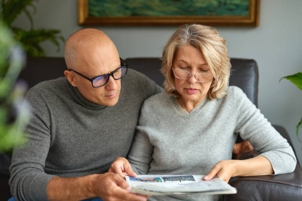 donna adulta e uomo che leggono il giornale. notizie, stampa, media, vacanze e concetto di persone - grandparent senior adult child reading foto e immagini stock