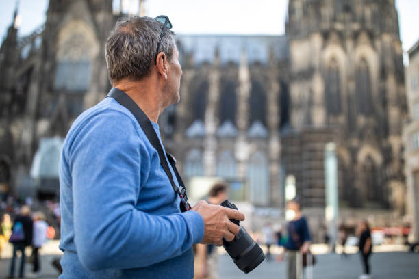 istock Photographer holding camera and looking around while standing in front of Cologne Cathedral 1220575701