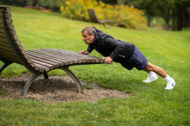 istock Mature man doing push-ups on bench in public park 1220575706