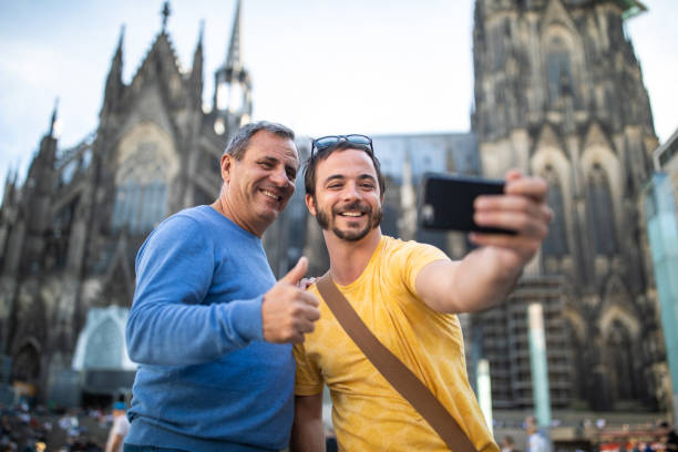 Father and son making taking a selfie in front of Cologne Cathedral on beautiful sprig day