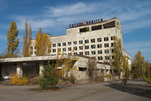 Digitally generated overgrown that vegetation encroaches upon an abandoned multi-story building in Pripyat, adorned with Soviet-era years 1917 and 1986 on its façade. An old firetruck sits forgotten in the foreground, symbolizing a silent witness to a once-thriving but now deserted city.\n\nThe scene was created in Autodesk® 3ds Max 2024 with V-Ray 6 and rendered with photorealistic shaders and lighting in Chaos® Vantage with some post-production added.