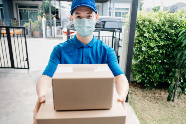 Asian Delivery man wearing mask send a package carton on front receiver shipping deliver social distancing while the virus is spreading and prevention crisis coronavirus covid-19 front home customer. el repartidor asiático que lleva máscara envía un paquete de cartón en el envío del receptor frontal entregar distanciamiento social mientras que el virus se está propagando y prevención coronavirus covid-19 cliente de primera línea de casa.
