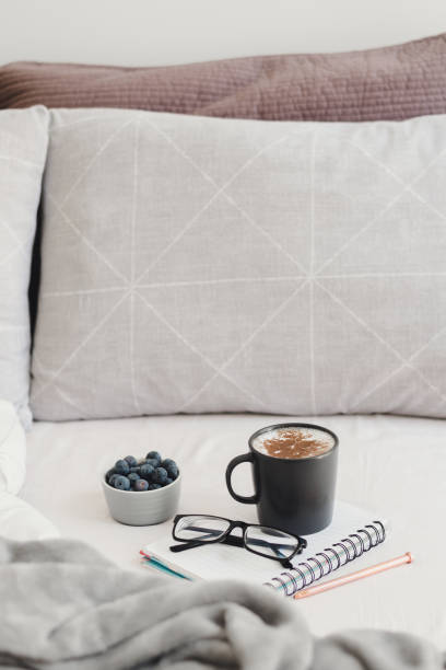 istock Breakfast in bed: cappuccino coffee with cinnamon powder and fresh blueberries served with note book, pen and reading glasses to work from home 1220581324