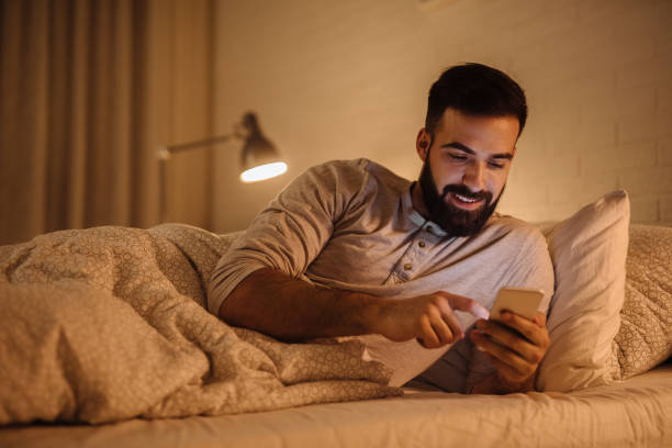 istock Handsome bearded man using phone in the bed at night 1220581436