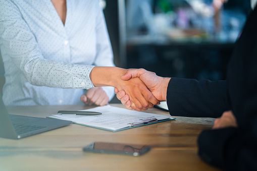Close-up shot of a business people shaking hands after signing contract.