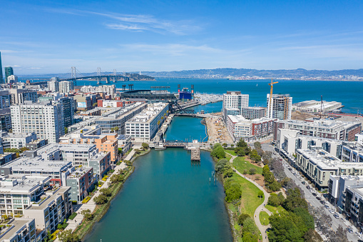 An aerial view of Mission Bay Canal on Channel Street in San Francisco. City skyline and Oracle Park in the background.