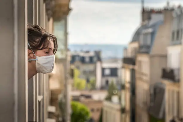 A Parisian girl looks outside the window during the quarantine because the containment of the virus is essential.