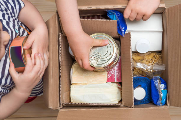 children opening a food delivery box at home, online ordering. grocery store delivery. box full of food in concept donation boxparcel. delivery during quarantine due to coronavirus covid-19 disease - food donation box groceries canned food imagens e fotografias de stock