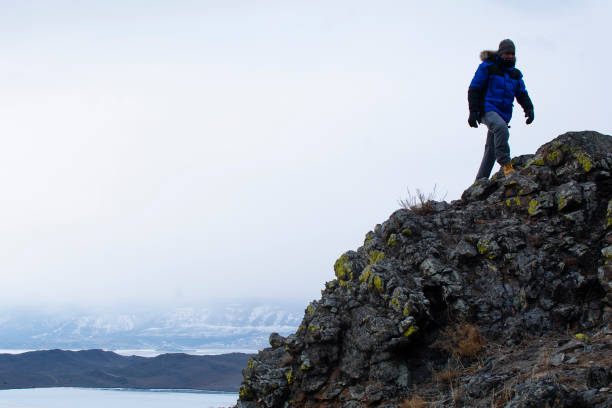 istock Man on cliff in winter, landscape photo 1220585093
