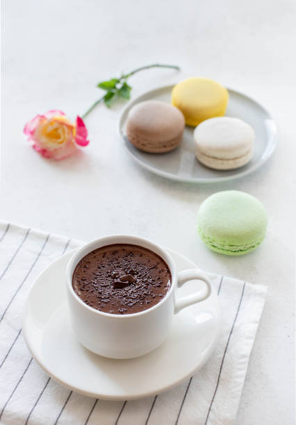 istock cup of hot chocolate with macarons flowers on a white background 1220585986