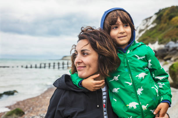 A young mother and her cute little son are walking by a sea - fotografia de stock