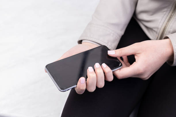 istock Hands with beautiful nails holds mobile phone with black screen. 1220589431