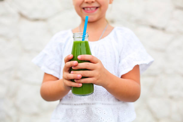 Little girl is drinking green fresh juice using straw outdoors Little girl is drinking green fresh juice using straw outdoors. Close up juice bar stock pictures, royalty-free photos & images