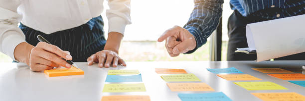 istock Midsection Of Colleagues Discussing At Desk In Office 1220591242