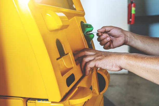 istock Hand inserting ATM card into bank machine and hand entering PIN/pass code on ATM/bank machine keypad to withdraw money 1220591361