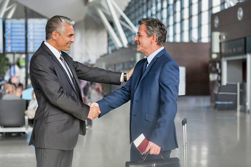 Mature businessman shaking hands with business partner in airport