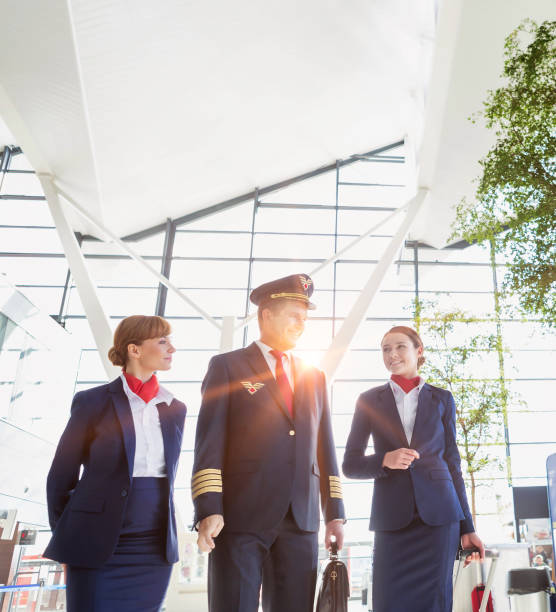 pilot with flight attendants walking in the airport - cabin crew pilot airport walking imagens e fotografias de stock