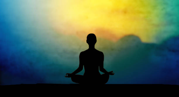 Night sky and silhouette of a human practicing yoga.
