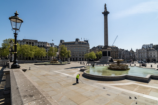 London, UK - April 23rd 2020:  Nelson Obelisk and deserted Trafalgar Falls with street sweeper during lockdown