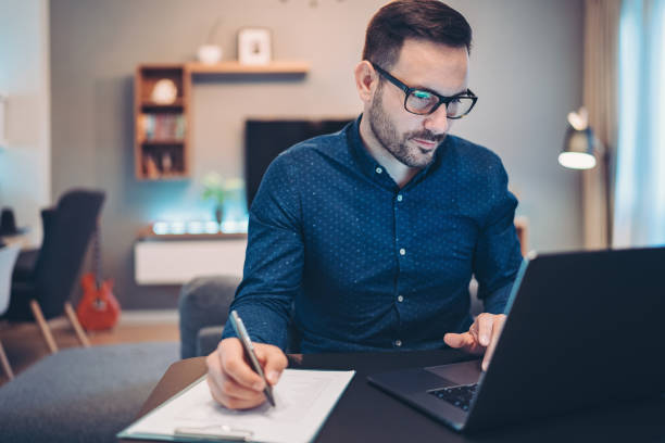 Worried businessman checking financial numbers Businessman using laptop and doing paperwork at home types of loans stock pictures, royalty-free photos & images