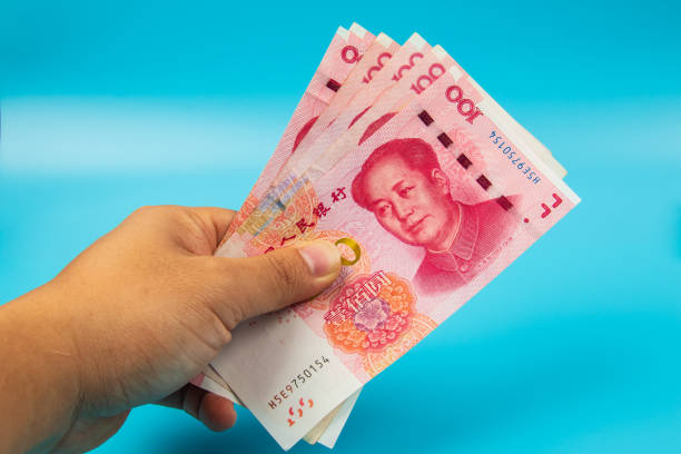 istock Man hand holding China Note RMB100 Yuan Note on blue background 1220602249