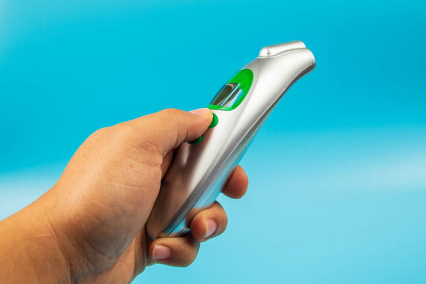 istock Man hand holding Temperature Measurement Device thermometer isolated on blue background 1220602289