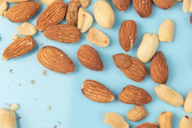 MIx nuts on Blue Background. Mixed nuts are a snack food consisting of any mixture of mechanically or manually combined nuts.