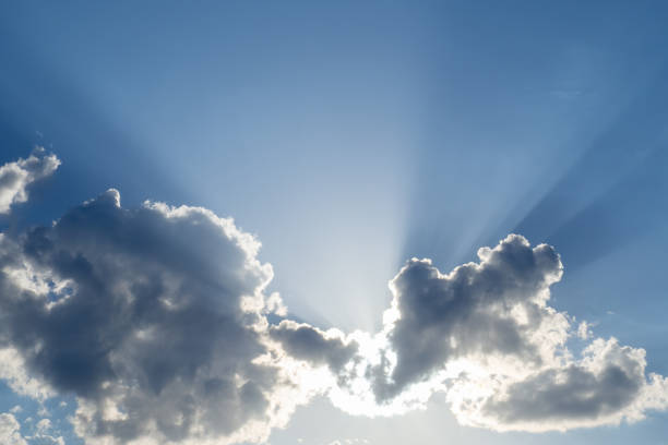 istock Sun shines behind the clouds, rays and shadows on blue sky. 1220603169