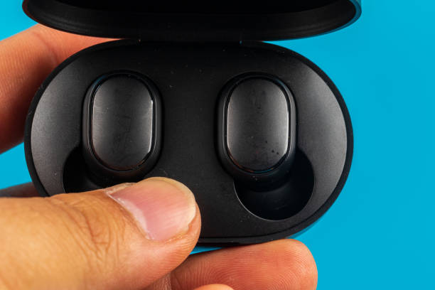 istock Man Hand with Wireless bluetooth headphones isolated on blue background 1220603571