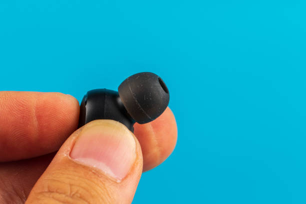 istock Man Hand with Wireless bluetooth headphones isolated on blue background 1220603593