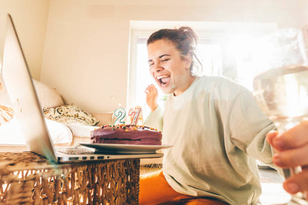Girl celebrating birthday online in quarantine time. Woman blowing out the candle on the birthday cake and making video call. Girl celebrating birthday online in quarantine time. virtual birthday celebration stock pictures, royalty-free photos & images