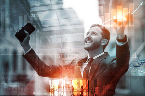 Double exposure portrait of a successful business man with arms up â success concepts