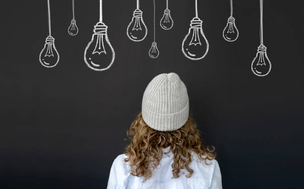 istock Creative woman thinking and facing a blackboard with light bulbs 1220609994