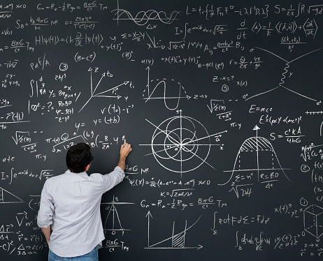 Physics teacher writing math equations on a blackboard